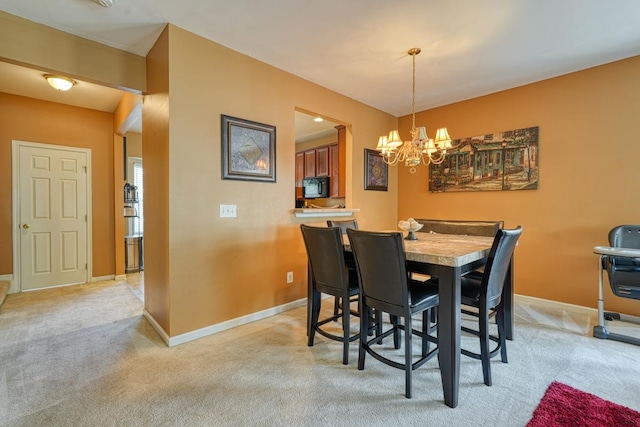 dining area featuring light carpet and an inviting chandelier