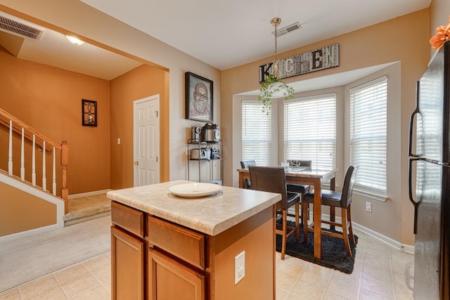 kitchen with stainless steel fridge, a center island, light tile patterned floors, and hanging light fixtures