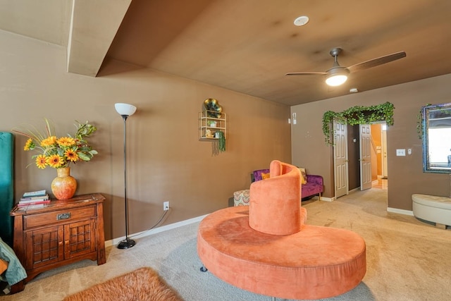 living area featuring light carpet and ceiling fan