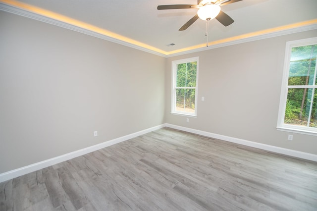 spare room with ceiling fan, crown molding, light wood-type flooring, and baseboards