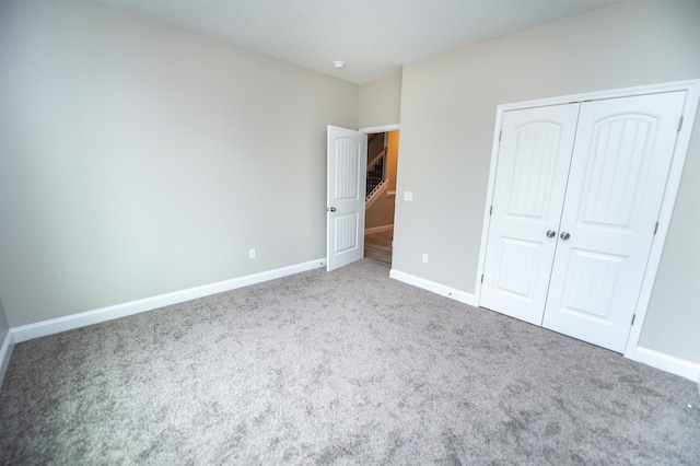 unfurnished bedroom with carpet floors, baseboards, and a closet