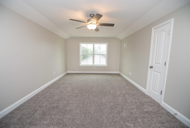 carpeted spare room with ceiling fan, vaulted ceiling, and baseboards