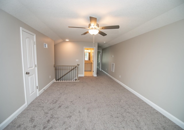 carpeted empty room featuring ceiling fan, baseboards, and lofted ceiling