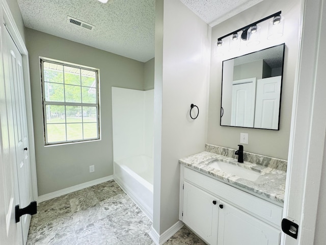 bathroom with a textured ceiling, vanity, and shower / tub combination