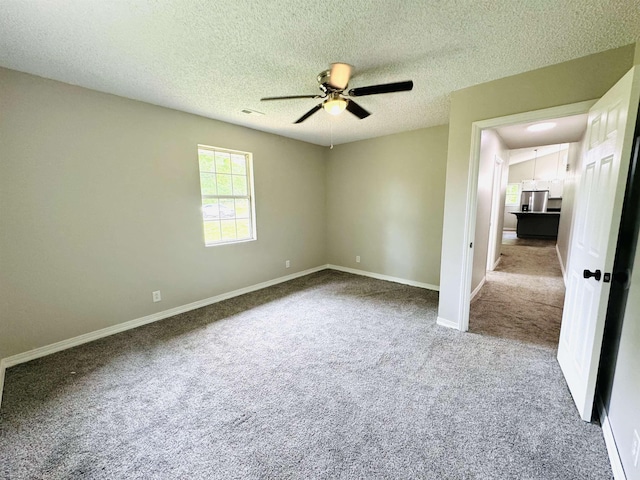 empty room featuring ceiling fan, carpet floors, and a textured ceiling