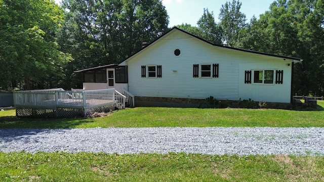 rear view of house featuring a yard, a wooden deck, and a sunroom