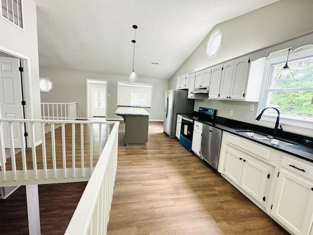 kitchen featuring white cabinetry, sink, stainless steel appliances, a textured ceiling, and decorative light fixtures