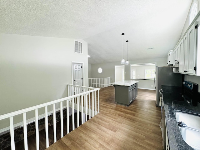 kitchen featuring a center island, white cabinets, vaulted ceiling, gray cabinets, and decorative light fixtures