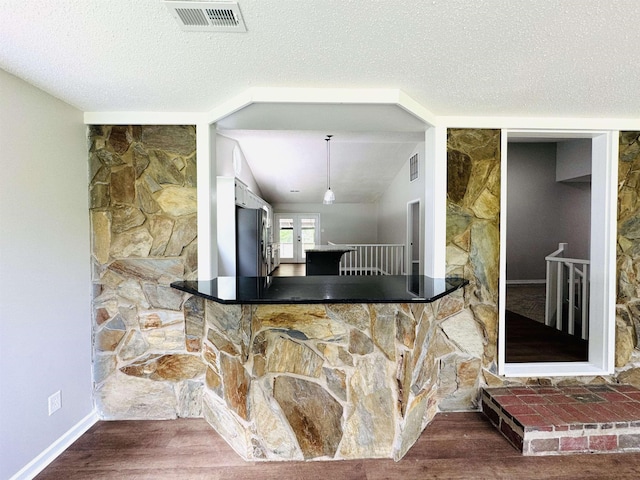 kitchen featuring vaulted ceiling, stainless steel refrigerator, wood-type flooring, and a textured ceiling