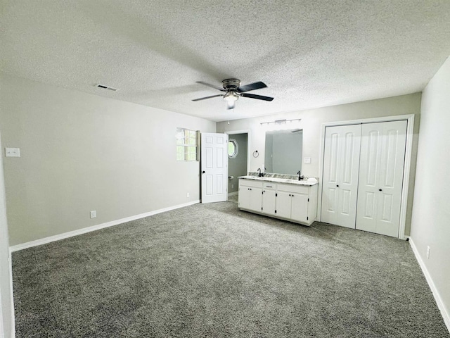 unfurnished bedroom with carpet flooring, ceiling fan, sink, and ensuite bathroom