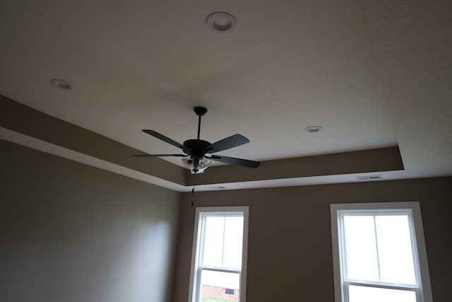 interior details featuring a raised ceiling and ceiling fan