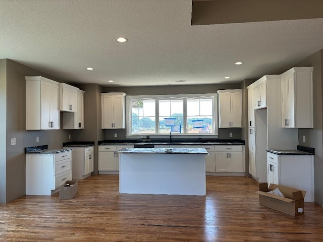 kitchen with hardwood / wood-style flooring, white cabinetry, a center island, and a textured ceiling