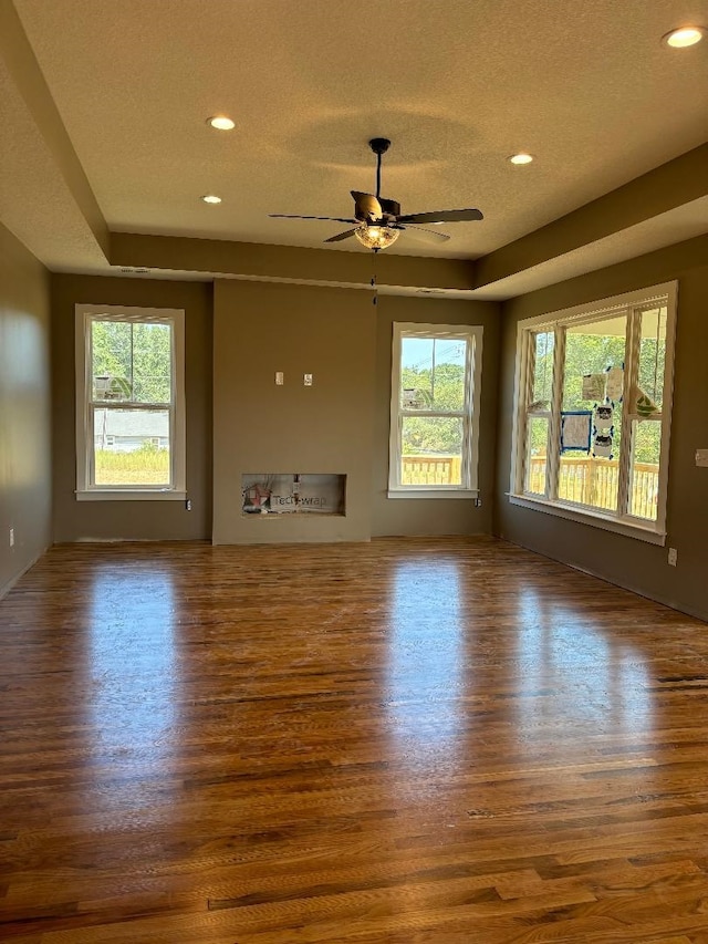 unfurnished living room with a healthy amount of sunlight, a textured ceiling, and dark hardwood / wood-style flooring