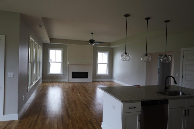 kitchen featuring pendant lighting, white cabinetry, sink, black dishwasher, and light stone countertops