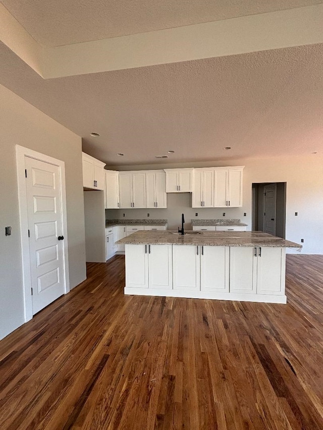 kitchen featuring white cabinetry, sink, dark hardwood / wood-style floors, and an island with sink