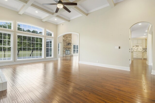 unfurnished living room with ceiling fan, hardwood / wood-style flooring, a fireplace, and beamed ceiling