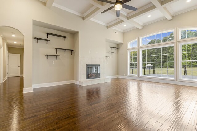 unfurnished living room with dark hardwood / wood-style flooring, a tiled fireplace, coffered ceiling, and beamed ceiling