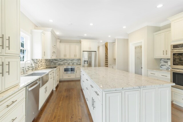 kitchen featuring stainless steel appliances, a center island, backsplash, and light stone counters