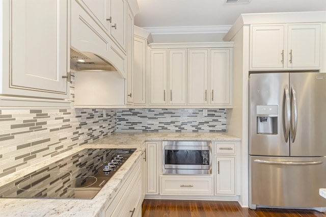 kitchen with crown molding, appliances with stainless steel finishes, white cabinetry, light stone counters, and decorative backsplash