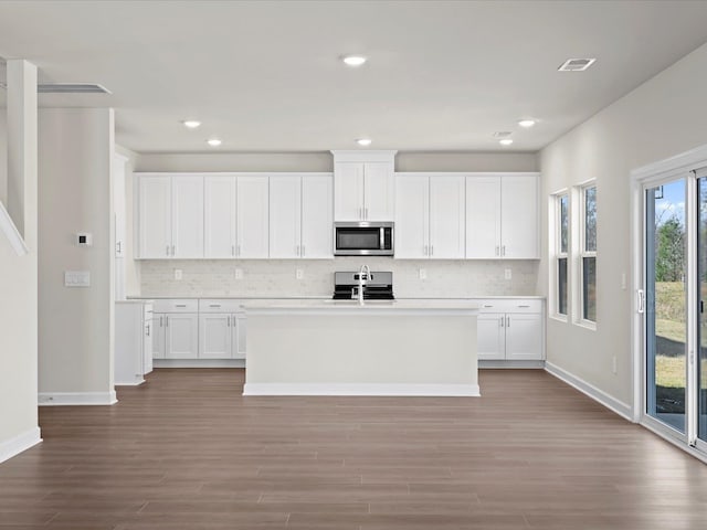 kitchen with white cabinetry, sink, an island with sink, and light wood-type flooring