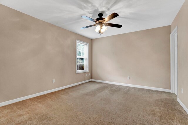 spare room featuring light colored carpet and ceiling fan