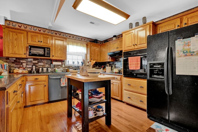 kitchen featuring light wood-type flooring, tasteful backsplash, and black appliances