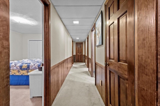 hall with light carpet and wood walls