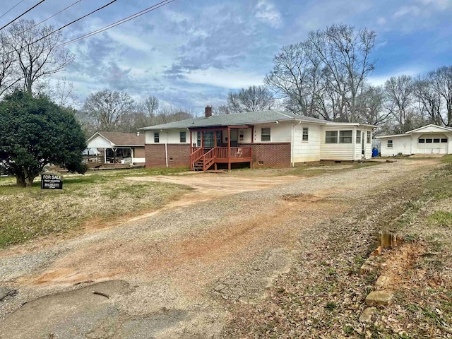 single story home with crawl space, a wooden deck, driveway, and a chimney