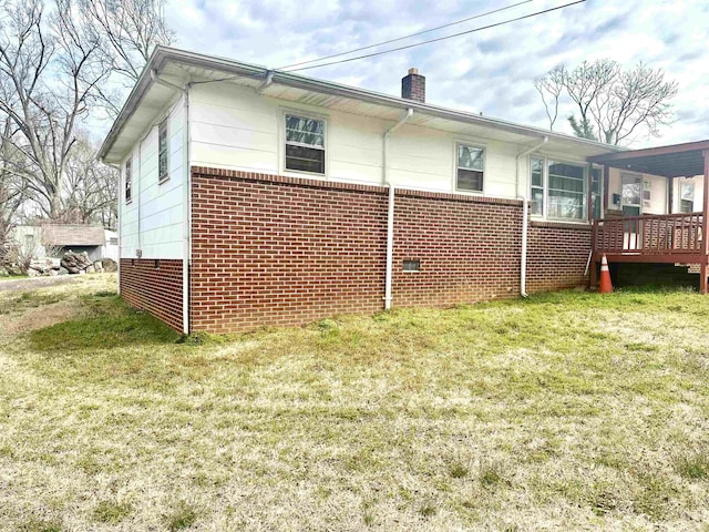 rear view of property featuring crawl space, brick siding, a chimney, and a lawn