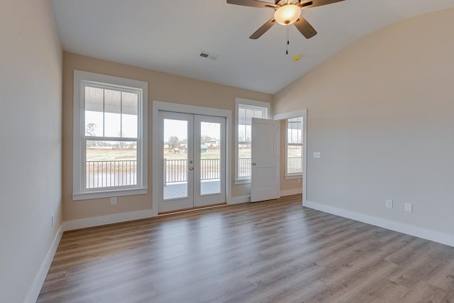 empty room featuring light hardwood / wood-style floors, vaulted ceiling, ceiling fan, and french doors