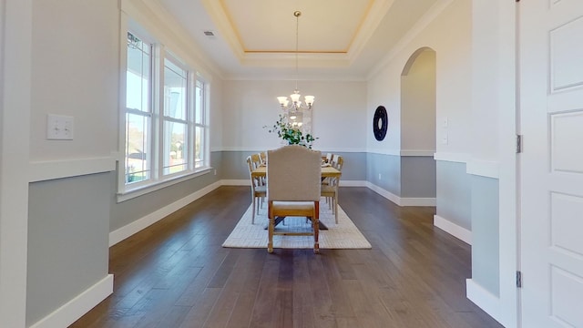 dining area featuring a notable chandelier, ornamental molding, a tray ceiling, and dark hardwood / wood-style flooring