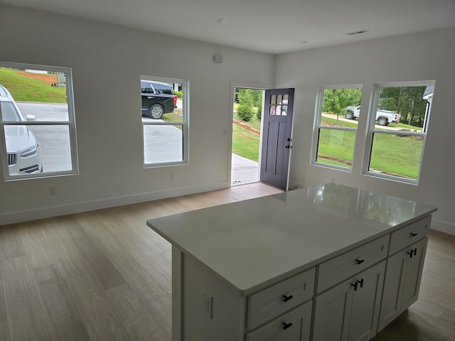 kitchen featuring gray cabinets, a kitchen island, a wealth of natural light, and light hardwood / wood-style flooring