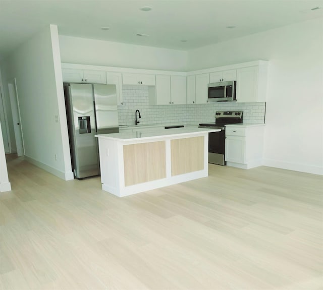 kitchen with decorative backsplash, stainless steel appliances, sink, a center island, and white cabinetry