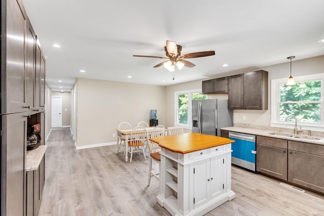 kitchen with sink, light hardwood / wood-style flooring, stainless steel appliances, dark brown cabinetry, and decorative light fixtures