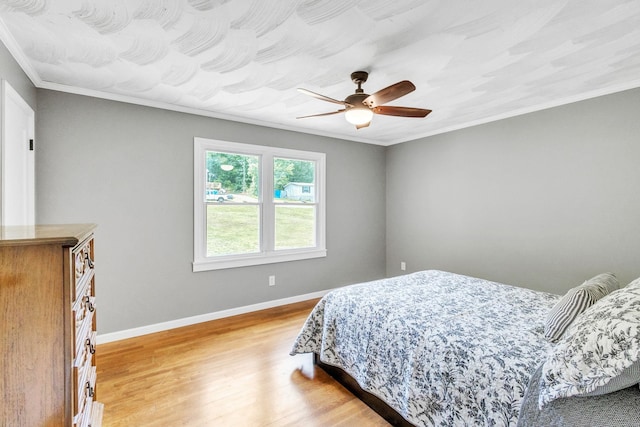 bedroom featuring hardwood / wood-style flooring, ornamental molding, and ceiling fan