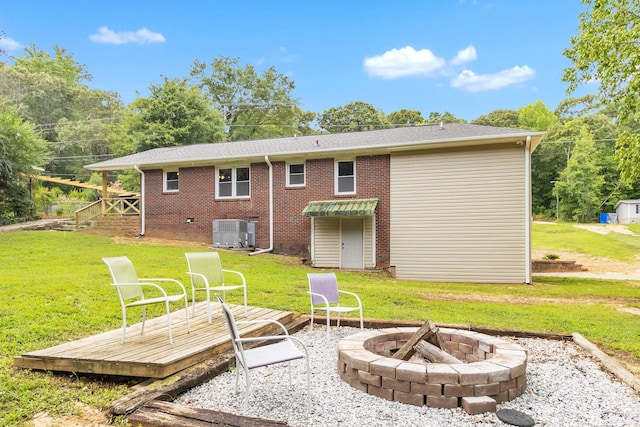 rear view of house featuring a wooden deck, an outdoor fire pit, central AC unit, and a lawn