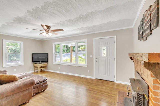 living room with light wood-type flooring, crown molding, a fireplace, and plenty of natural light