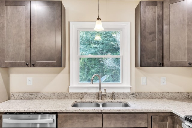 kitchen featuring dishwasher, sink, light stone counters, and decorative light fixtures