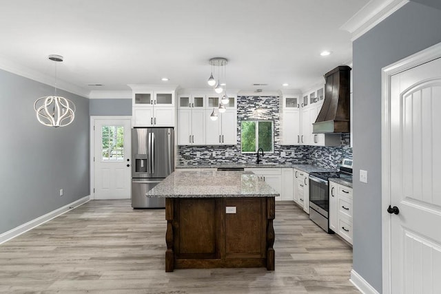 kitchen with custom exhaust hood, stainless steel appliances, decorative backsplash, ornamental molding, and a sink