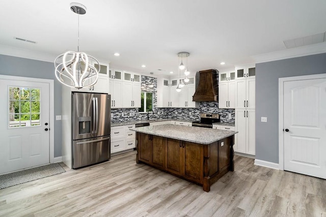 kitchen with a chandelier, stainless steel appliances, premium range hood, visible vents, and decorative backsplash