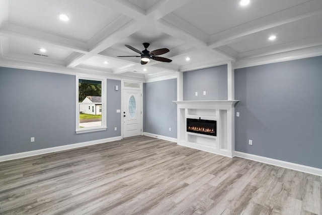 unfurnished living room with beam ceiling, wood finished floors, coffered ceiling, a lit fireplace, and baseboards