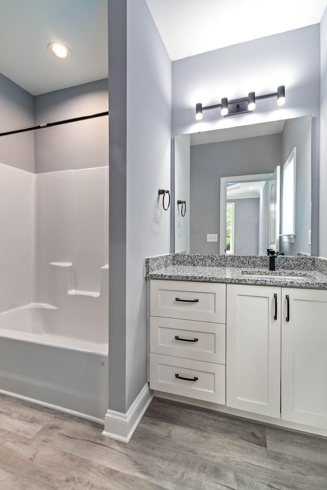 bathroom featuring  shower combination, vanity, baseboards, and wood finished floors