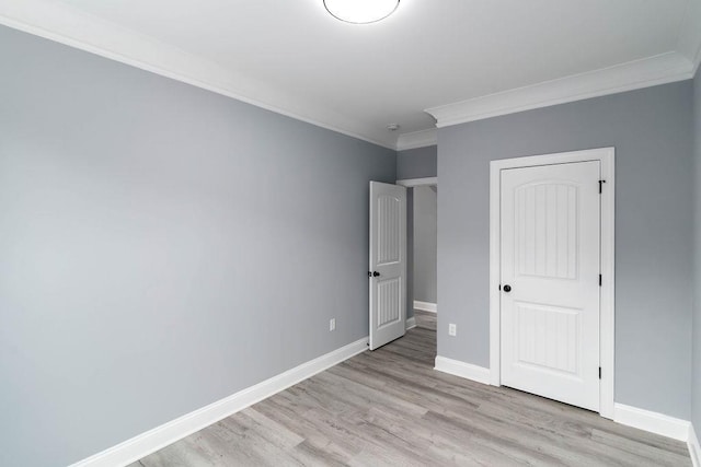 unfurnished bedroom featuring light wood-style flooring, baseboards, and crown molding