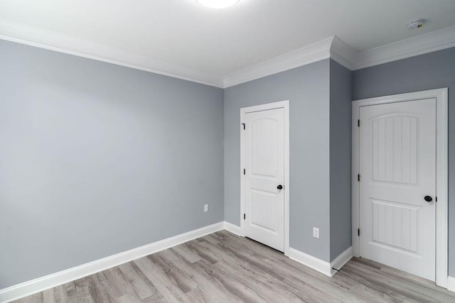 unfurnished bedroom with crown molding, light wood-type flooring, and baseboards