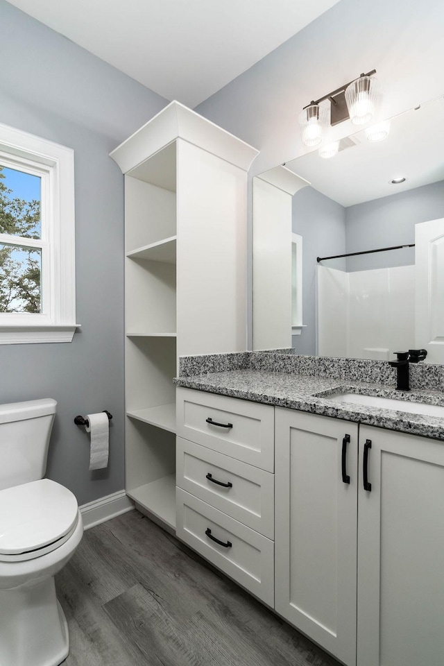 bathroom featuring toilet, baseboards, wood finished floors, and vanity