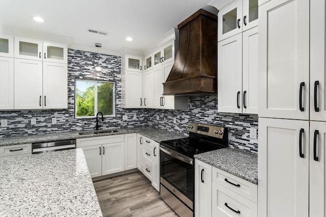 kitchen featuring custom exhaust hood, visible vents, appliances with stainless steel finishes, white cabinets, and a sink