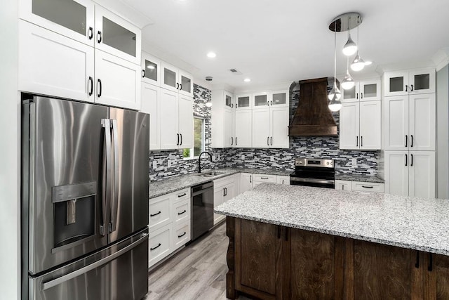 kitchen with decorative backsplash, appliances with stainless steel finishes, custom exhaust hood, white cabinetry, and a sink