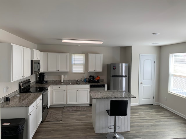 kitchen featuring white cabinetry, wood-type flooring, a center island, and appliances with stainless steel finishes