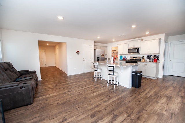 kitchen featuring a kitchen island, a breakfast bar, white cabinetry, dark hardwood / wood-style flooring, and stainless steel appliances