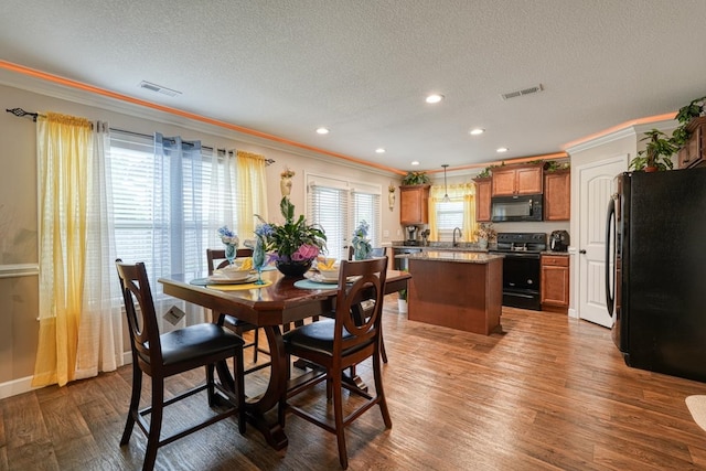 dining room featuring a textured ceiling, ornamental molding, and hardwood / wood-style floors